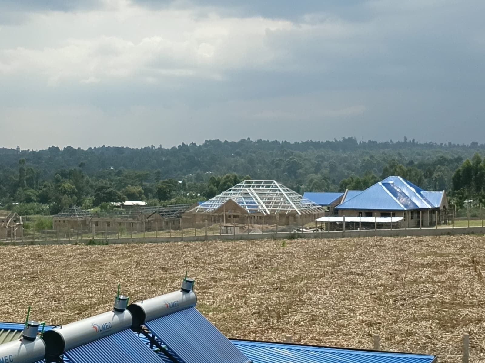 Solar water heaters on blue roofs during campus construction at Sirisia